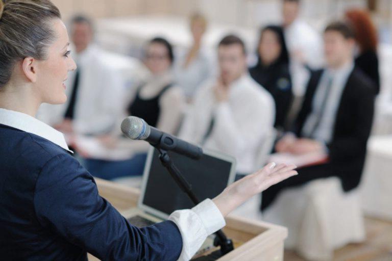 person at podium in front of audience